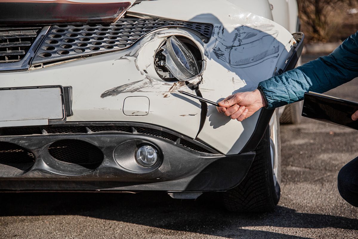 Insurance agent will examine and examine the damage to the car after an accident. Inspection of the car after an accident on the road. The front fender and right headlight are broken, damaged and scratched on the bumper.