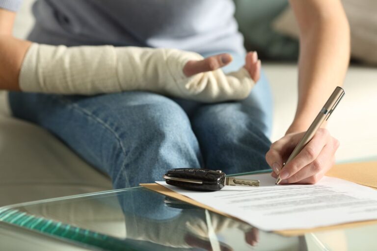 Close up of a lady hands with broken arm signing insurance document after car accident