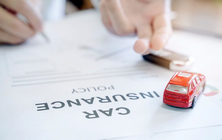 Car insurance policy with red car toy and blur image of man hand for vehicle insurance policy concept.